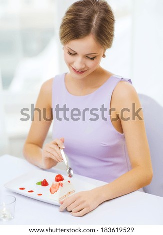 restaurant, people and holiday concept - smiling young woman eating dessert at restaurant