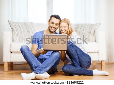 love, family, technology, internet and happiness concept - smiling happy couple with laptop computer sitting on the floor at home