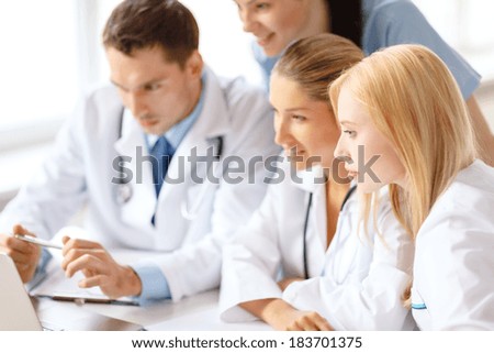 healthcare, medical and technology concept - smiling group of doctors looking at laptop computer in hospital