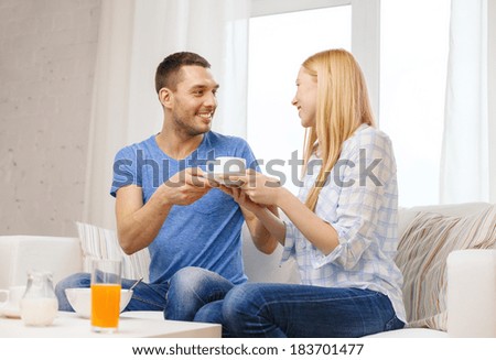 love, family, healthy food and happiness concept - smiling man giving his girlfriend or wife cup of coffee at home