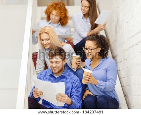 business, office and startup concept - smiling creative team with papers and take away coffee on staircase