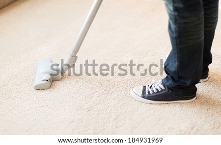 cleaning and home concept - close up of male hoovering carpet