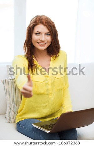 home, technology and internet concept - smiling woman sitting on the couch with laptop computer and showing thumbs up at home