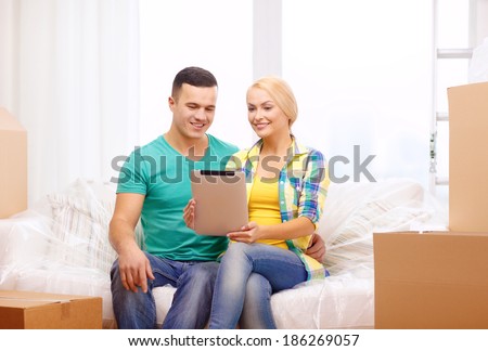 moving, home, technology and couple concept - smiling couple relaxing on sofa with tablet pc computer in new home