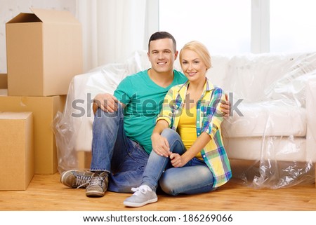 moving, home and couple concept - smiling couple sitting on the floor in new house