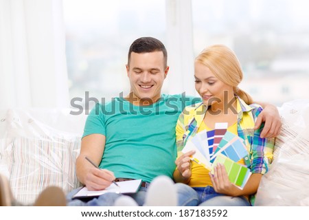 moving, home and couple concept - smiling couple looking at color samples in new home