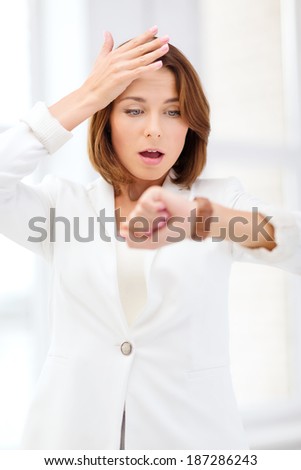 business and time management concept - stressed businesswoman looking at wrist watch in office