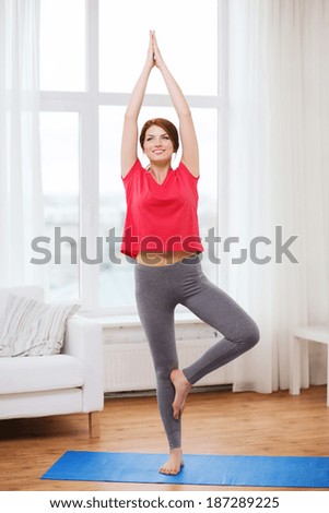 fitness, home and diet concept - smiling redhead teenager meditating at home
