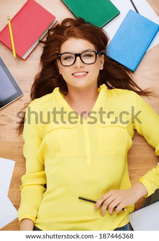 education and home concept - smiling redhead female student in eyeglasses lying on floor with pencil
