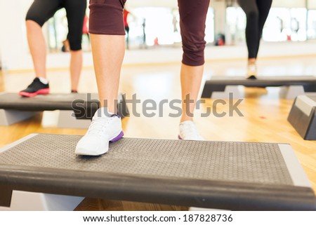 fitness, sport, training, gym and lifestyle concept - close up of women legs steping on step platform in gym