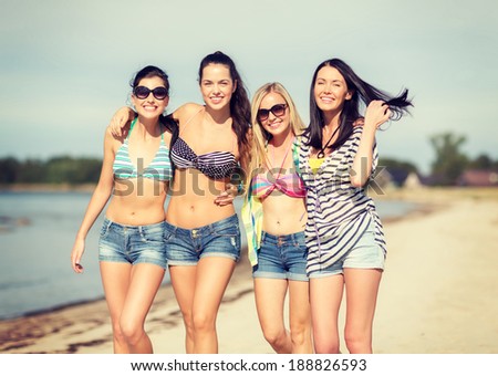 summer, holidays, vacation, happy people concept - group of girls in bikinis walking on the beach