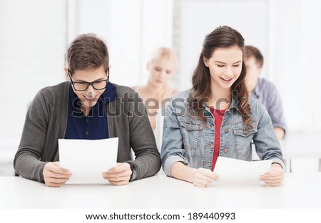 education, technology and internet concept - two teenagers looking at test or exam results