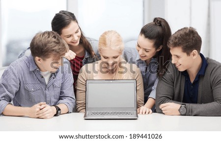 education, technology, advertisement and internet concept - group of smiling students looking at blank black laptop screen