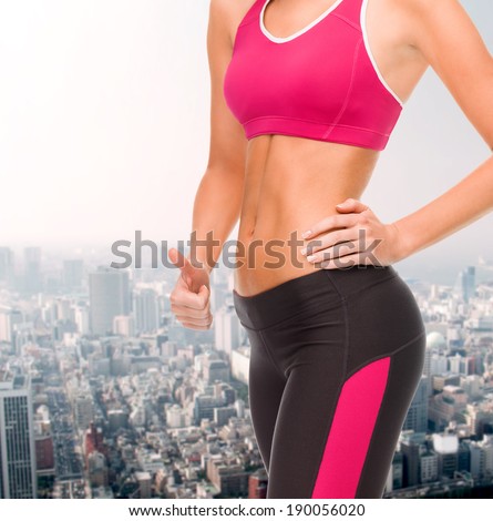 fitness and diet concept - close up of female abs and hand showing thumbs up