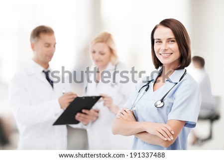 healthcare and medical concept - young female doctor with colleagues in hospital