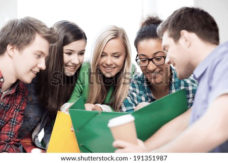 education concept - students looking at notebook at school