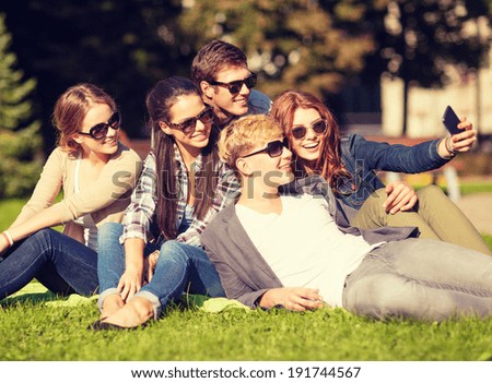summer holidays and teenage concept - group of teenagers taking selfie in park with smartphone
