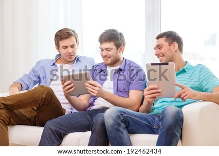 friendship, technology and home concept - smiling male friends with tablet pc computers at home