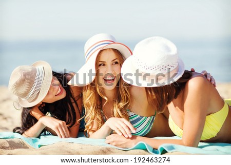summer holidays and vacation - girls in bikinis sunbathing on the beach