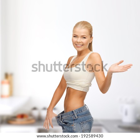 fitness, diet and healthcare concept - sporty woman showing big pants
