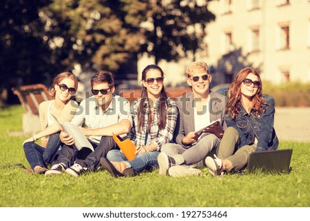 summer, internet, education, campus and teenage concept - group of students or teenagers with laptop, notebooks and folders