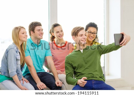 education and technology concept - smiling students taking selfie with tablet pc computer at school