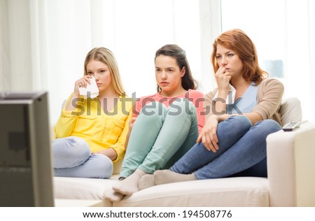 home, technology and friendship concept - three sad teenage girl watching tv at home