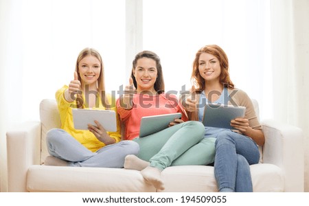 friendship, technology and internet concept - three smiling teenage girls with tablet pc computers at home showing thumbs up