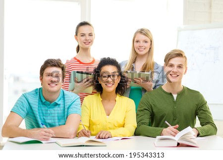education, technology and school concept - five smiling students with textbooks, tablet pc computers and books at school