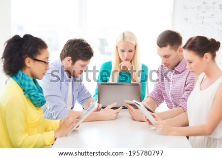 business, office, technology and startup concept - serious creative team with table pc and laptop computers working in office
