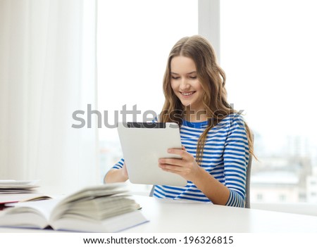 education, technology and home concept - happy smiling student girl with tablet pc computer and books at home