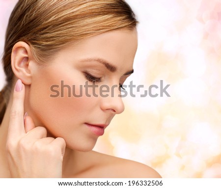 health and beauty concept - face of beautiful woman touching her ear