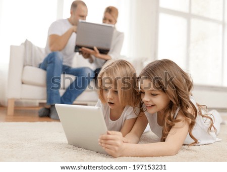 family, children, technology and home concept - smiling sister with tablet pc computer and parents on the back with laptop