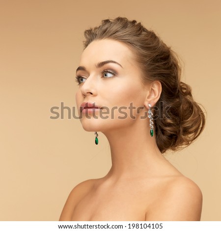 beauty and jewelry concept - beautiful woman in diamond and emerald earrings