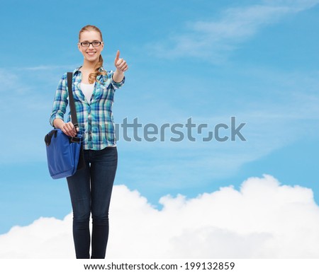 education and people concept - smiling female student in eyeglasses with laptop bag showing thumbs up over blue sky background