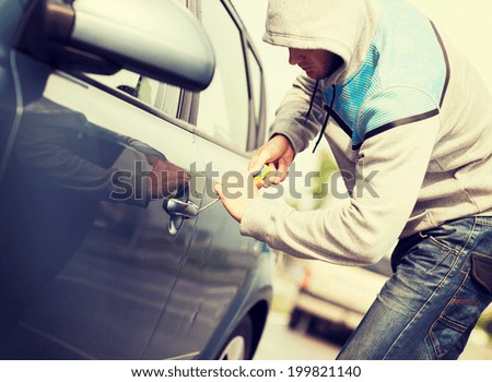 transportation, crime and ownership concept - thief breaking the car lock