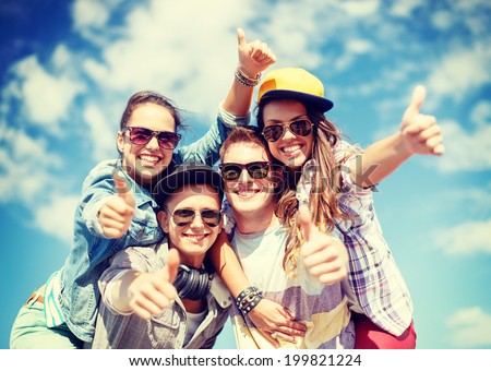 summer holidays and teenage concept - group of smiling teenagers in sunglasses hanging outside and showing thumbs up