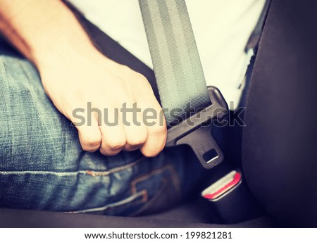 transportation and vehicle concept - man fastening seat belt in car