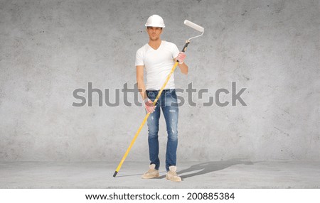 construction and building concept - handsome painter in helmet with paint roller over concrete wall