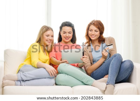 friendship, money, technology and internet concept - three smiling teenage girls with tablet pc computer and credit card at home