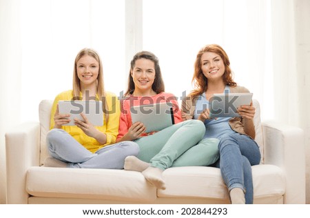 friendship, technology and internet concept - three smiling teenage girls with tablet pc computers at home
