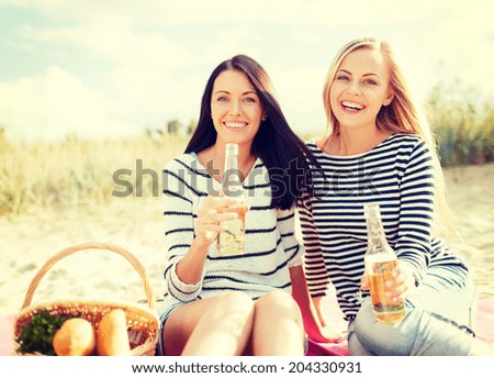 summer, holidays, vacation, happy people concept - smiling girlfriends with bottles of beer or non-alcoholic drinks on the beach
