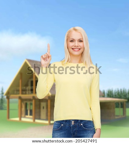 advertisement concept - attractive young woman in casual clothes pointing her finger up