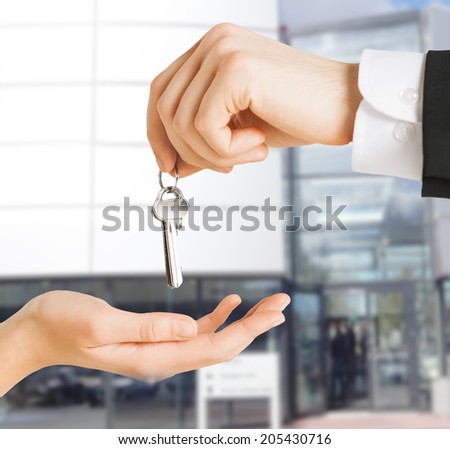 real estate concept - picture of man hand passing house keys to woman