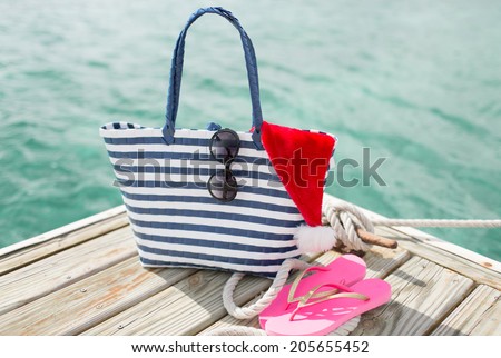 beach, summer, vacation, christmas and accessories concept - close up of beach accessories and santa helper hat on wooden pier