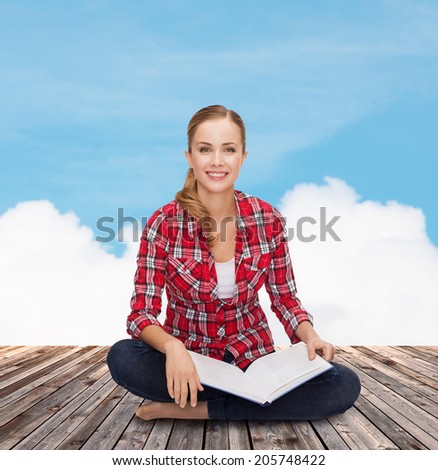 education and leisure concept - smiling young woman sitting on floor with book