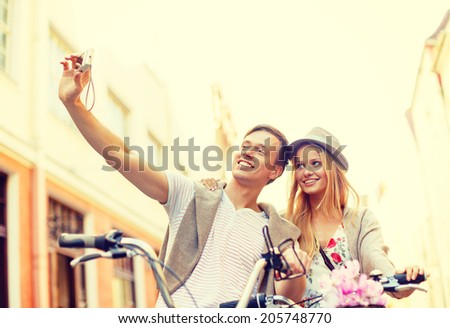 summer holidays, travel, vacation, tourism and dating concept - travelling couple with bicycles taking photo picture with camera