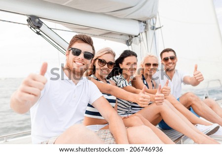 travel, sea, friendship, gesture and people concept - smiling friends sitting on yacht deck and showing thumbs up