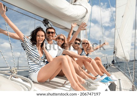 vacation, travel, sea, friendship and people concept - smiling friends sitting on yacht deck and greeting