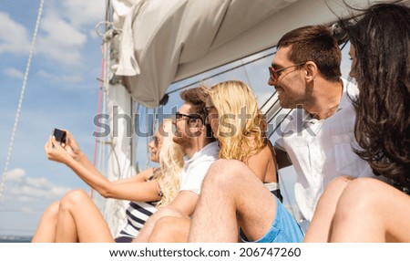 vacation, travel, sea, friendship and people concept - smiling friends sitting on yacht deck and making selfie